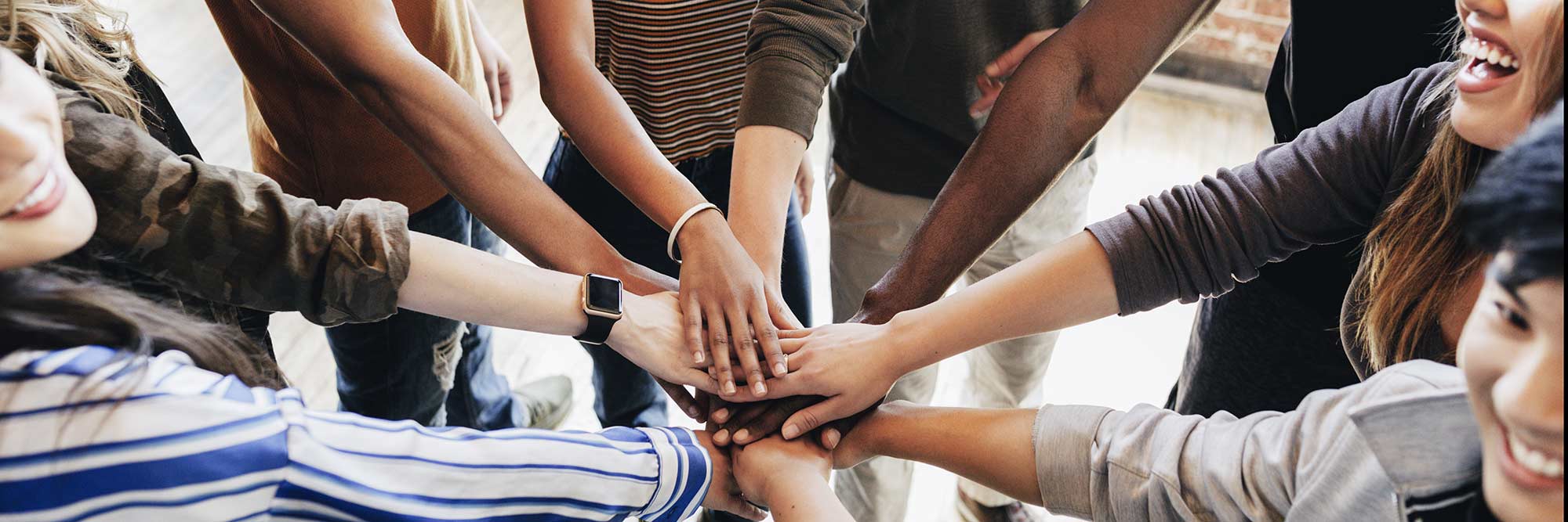 group of young adults with hands over each other in circle